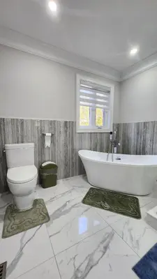 a white bathroom with a tub and a toilet at Toronto Guest House in Toronto