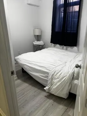 a bedroom with a white bed and a wooden floor at Ame place in Brampton