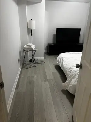 a bedroom with a bed and a table with a lamp at Ame place in Brampton