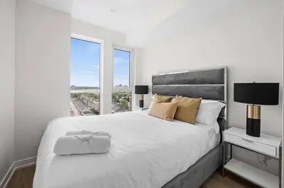 a white bedroom with a large bed and a window at Elegant 4BR Condo with City Views & Free Parking in Toronto