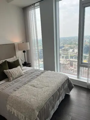 a bedroom with a large bed with large windows at INFIVILLA King Suites & Towers Eaton Toronto in Toronto