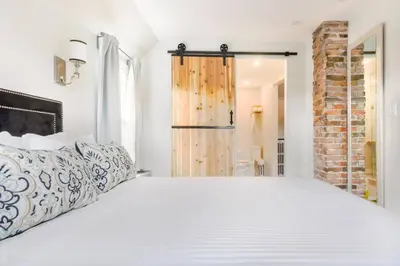 a bedroom with a white bed and a brick wall at Stylishly Remodeled Queen Victoria Loft in Niagara Falls