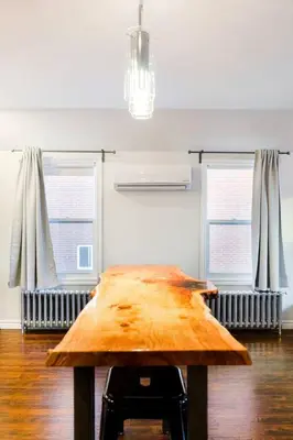 a wooden table in the middle of a room with windows at Stylishly Remodeled Queen Victoria Loft in Niagara Falls