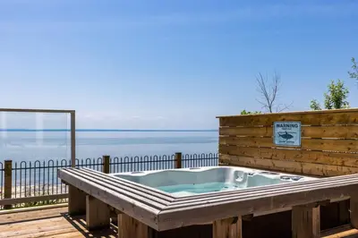 a hot tub on a deck with a view of the water at Crystal Beach Executive Waterfront Lakehouse in Fort Erie