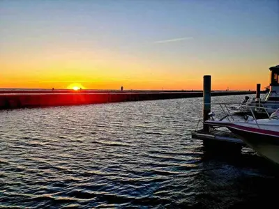 a boat is docked at a dock with the sunset at Bobs Yer Uncle in Port Dalhousie in St. Catharines