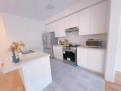 a kitchen with white cabinets and a stove top oven at Vantage stay Modern 4BR townhouse pickering in Pickering
