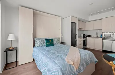 a bedroom with a large bed and a kitchen at Modern Studio Condo Yonge Street Downtown Toronto in Toronto