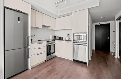 a kitchen with white cabinets and stainless steel appliances at Modern Studio Condo Yonge Street Downtown Toronto in Toronto