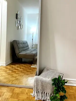 a living room with a chair and a mirror at Toronto Upper Beaches Apartment in Toronto