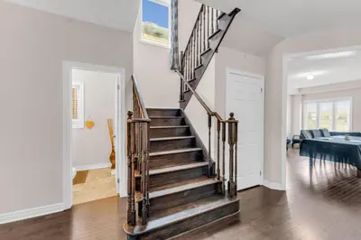 a staircase in a home with white walls and wooden floors at Luxury Home Mins from Waterfall next to Transit in Niagara Falls