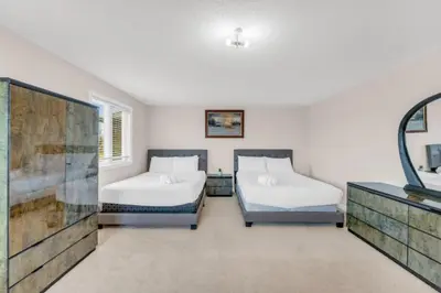 a bedroom with two beds and a mirror at Luxury Home Mins from Waterfall next to Transit in Niagara Falls
