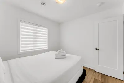 a white bedroom with a bed and a window at 5 Mins to the Falls Brand New Home in Niagara Falls