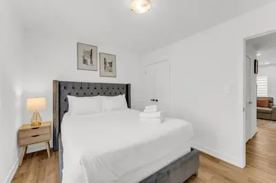 a white bedroom with a large bed and a table at 5 Mins to the Falls Brand New Home in Niagara Falls