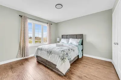 a white bedroom with a bed and a window at Luxury Mansion with Chefs Kitchen by Niagara Falls in Thorold
