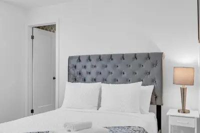 a bedroom with a large bed with a gray headboard at New 2BD Townhouse Mins from Niagara Falls in Niagara Falls