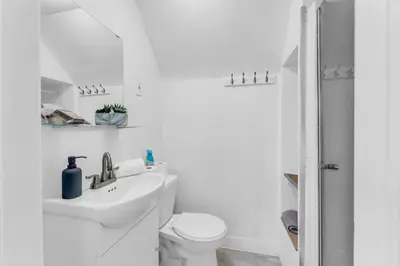 a white bathroom with a toilet and a sink at Cozy Home Short Walk to Falls Nintendo FirePit in Niagara Falls