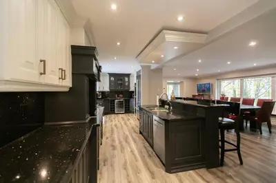a kitchen with black counter tops and a dining room at Luxury 4BR Stay with Swim Spa, Golf and Fireplaces in Caledon