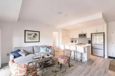 a living room with a couch and a kitchen at Modern 2BR Getaway with Balcony, BBQ and Parking in Innisfil