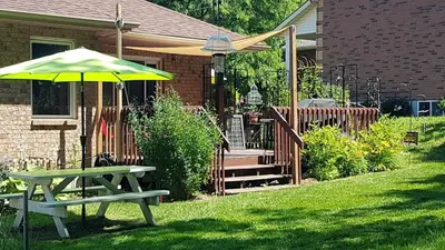 a picnic table and an umbrella in front of a house at White Rolling Sands of Penetang by Theatre in Penetanguishene