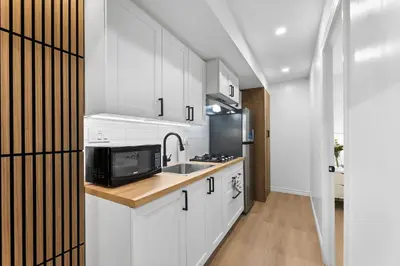 a kitchen with white cabinets and a sink and a microwave at High Park Grove Modern 1B1B, Kitchen, Laundry in Toronto
