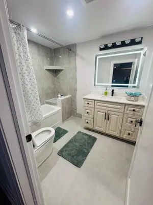 a bathroom with a toilet and a sink and a mirror at Hearth & Home Spacious Suite in Pickering