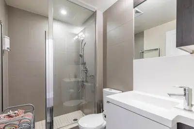 a white bathroom with a shower and a toilet at Modern 1 Bedroom Condo Front Street Downtown Toronto in Toronto