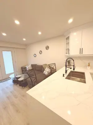 a kitchen and living room with a couch and a counter at Modern 1-BR Suite EV Charger, Backyard BBQ & Near Square One in Mississauga