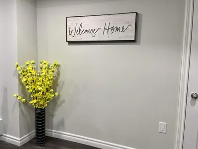 a vase with yellow flowers on a wall with a picture at Master bedroom in Mississauga