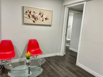 a room with two red chairs and a glass table at Master bedroom in Mississauga