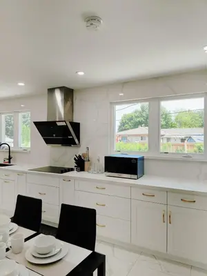 a kitchen with white cabinets and a table with chairs at 5 Bed 4Bath 9 Parking Lakeside Retreat in Ajax