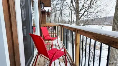 three red chairs sitting on a porch in the snow at Winter at Wildwood in Bailieboro