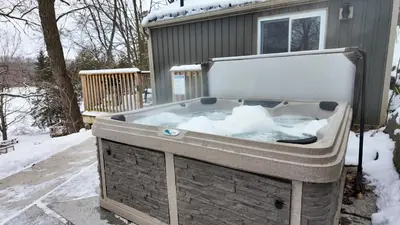 a jacuzzi tub with snow in front of a house at Winter at Wildwood in Bailieboro