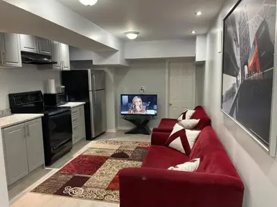 a living room with a red couch and a tv at Peace Apartment in Brampton
