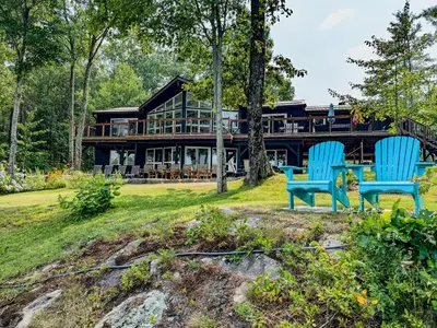 two blue chairs sitting in front of a house at Private Lakefront Cottage Living on Muldrew Lake in Gravenhurst