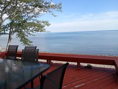 a table and chairs on a deck overlooking the water at Lakeside Villa across Whisky Run Golf Club in Port Colborne