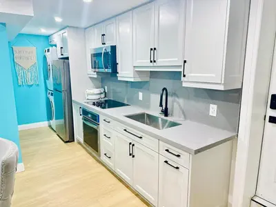 a kitchen with white cabinets and a stainless steel refrigerator at Modern 2BR suite Kitchen Workspace Laundry in London
