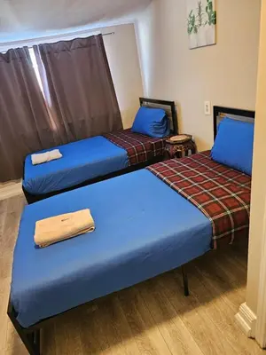 two beds in a room with blue sheets at Toronto Holiday Home in Toronto
