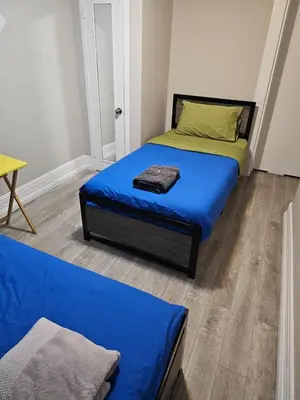 a bedroom with two beds with blue sheets and a yellow pillow at Toronto Holiday Home in Toronto