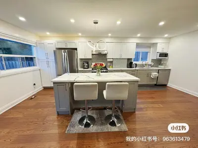 a kitchen with white cabinets and a island with two chairs at Quiet Queen Bedroom near Finch Birchmunt in Toronto