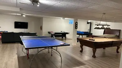 a living room with a ping pong table and a couch at Family friendly place with pool in Penetanguishene