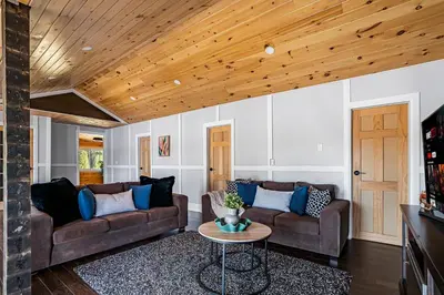 a living room with two couches and a table at Rustic Lakefront Cottage with Fire Pit & Scenic Views in Brechin