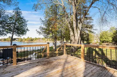 a wooden deck with a fence and a tree at Rustic Lakefront Cottage with Fire Pit & Scenic Views in Brechin