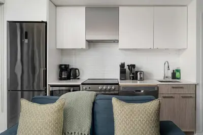 a kitchen with white cabinets and a blue couch at Chic 2BR Condo Toronto Core Steps to Eaton Centre in Toronto