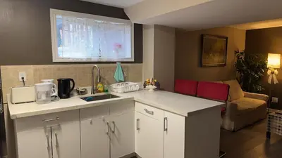 a kitchen with white cabinets and a couch in a living room at Cozy Private Basement Suite Beside Plaza Free Parking Walk to Groceries & Dining in Richmond Hill