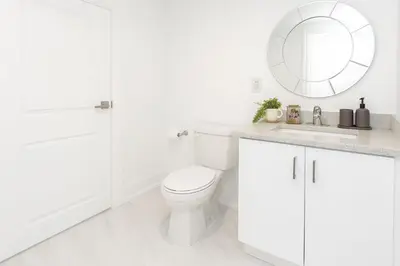 a white bathroom with a toilet and a mirror at Bright 2 Bed Basement Near Square One Mall Family Friendly Stay in Mississauga