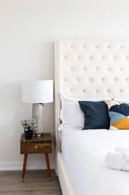 a bedroom with a white bed and a table with a lamp at Spacious 3BR Loft with Balcony and Free Parking in Toronto