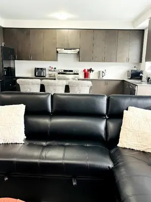 a black leather couch in front of a kitchen at Cozy Private Room with ensuite in Shared Home in Ayr in Paris