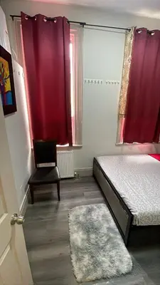 a bedroom with two beds and a chair and red curtains at Homestay At Queen St-Downtown Toronto-Free Wifi N in Toronto