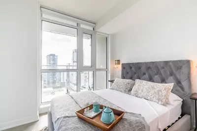a bedroom with a bed with a tray of dishes on it at VOGUE Suites Toronto Downtown - Entertainment District in Toronto
