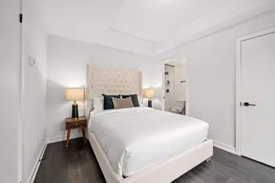 a white bedroom with a large bed and two lamps at Chic 2-Bedroom Apartment with Parking in Toronto